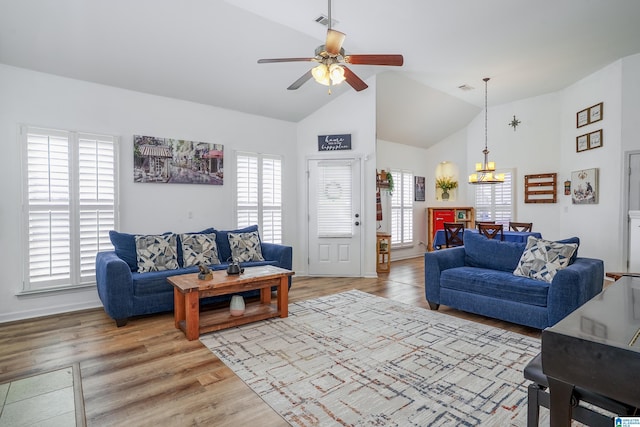 living room featuring light wood-style flooring, visible vents, a wealth of natural light, and ceiling fan with notable chandelier