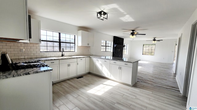 kitchen with plenty of natural light, a sink, a ceiling fan, a peninsula, and backsplash