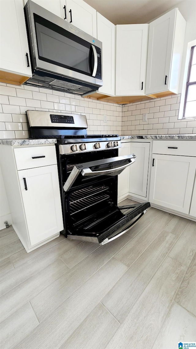 kitchen with stainless steel appliances, white cabinets, and decorative backsplash