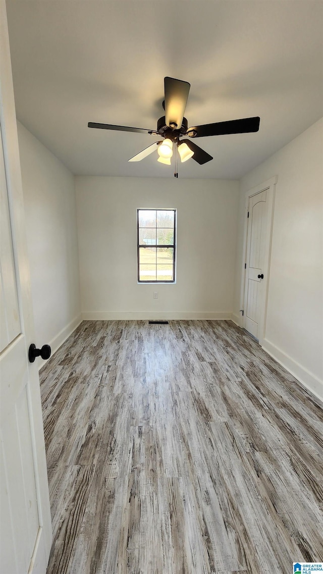 empty room with baseboards, a ceiling fan, and wood finished floors