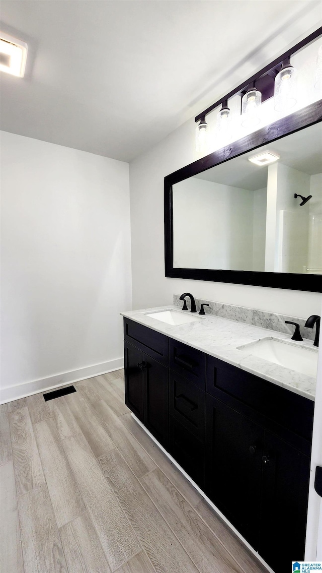 bathroom with double vanity, a sink, and wood finished floors