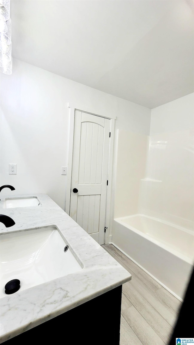 bathroom with a sink, double vanity, and wood finished floors
