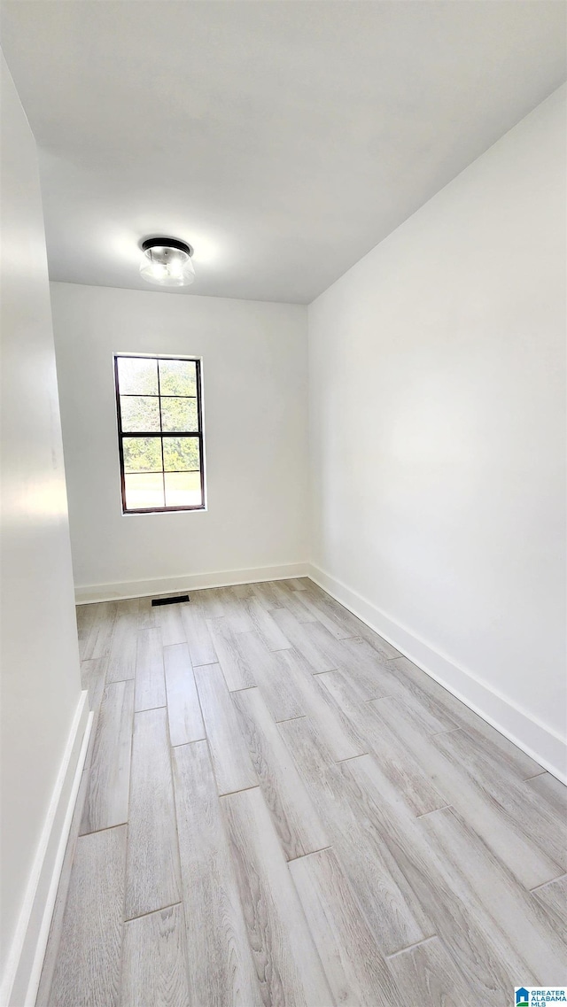 empty room featuring light wood finished floors, visible vents, and baseboards