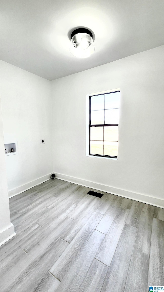 spare room with baseboards and wood finished floors