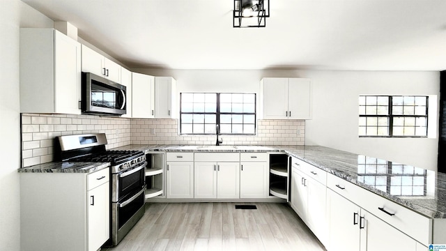 kitchen with a sink, light stone countertops, a peninsula, and stainless steel appliances