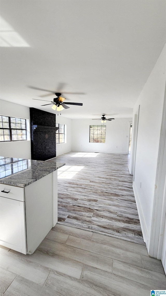 interior space featuring ceiling fan, light wood-style floors, and baseboards