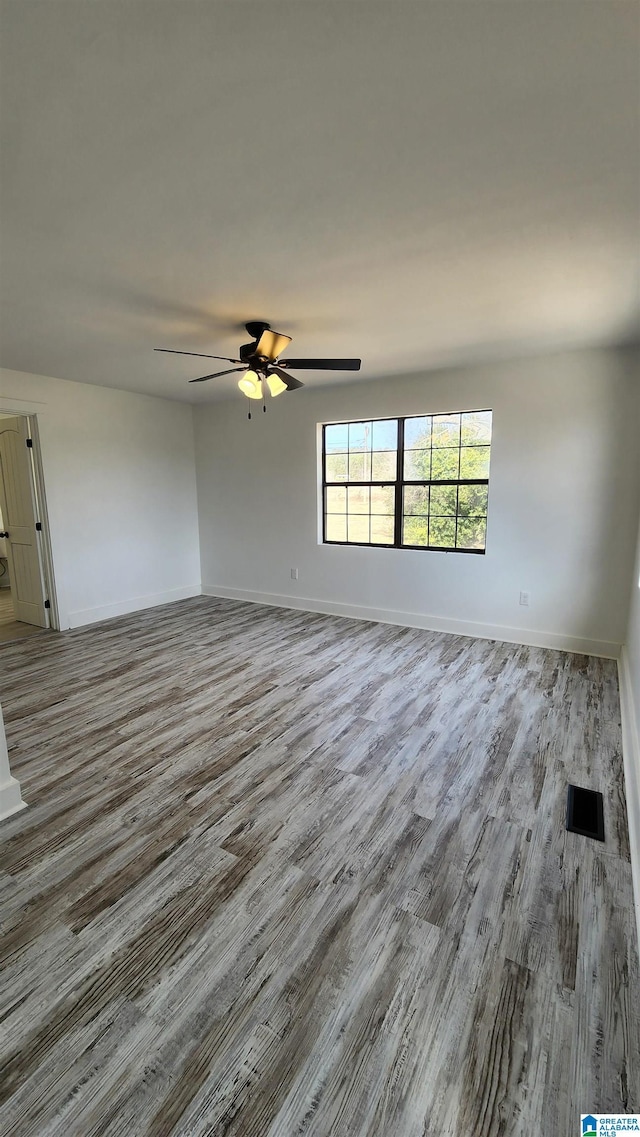 unfurnished room with baseboards, a ceiling fan, and wood finished floors