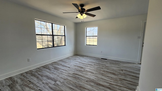 unfurnished room featuring visible vents, baseboards, a ceiling fan, and wood finished floors