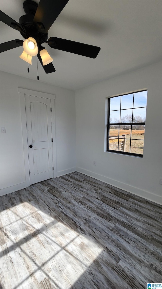 empty room featuring baseboards, a ceiling fan, and wood finished floors