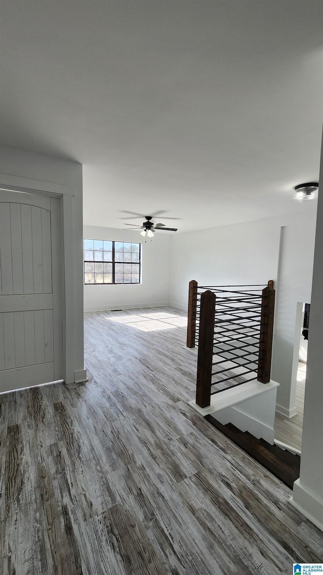 unfurnished living room with baseboards, a ceiling fan, and wood finished floors
