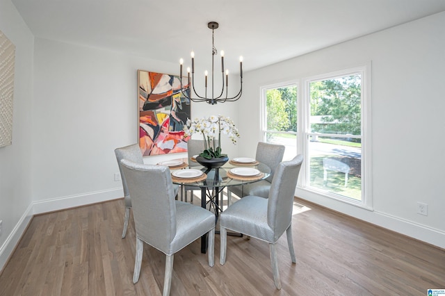 dining area featuring a notable chandelier, baseboards, and wood finished floors