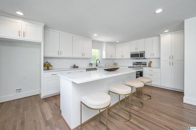 kitchen featuring light countertops, white cabinets, appliances with stainless steel finishes, and light wood-style floors