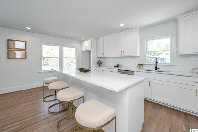 kitchen with a kitchen bar, tasteful backsplash, a sink, and white cabinets