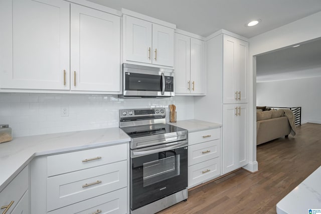 kitchen with dark wood-type flooring, white cabinets, appliances with stainless steel finishes, and decorative backsplash