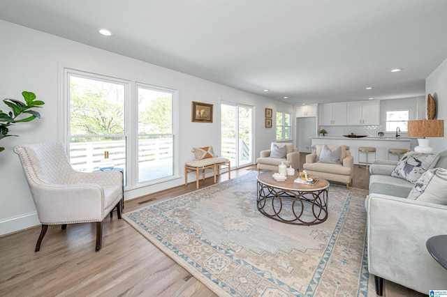 living room featuring light wood-style floors, baseboards, visible vents, and recessed lighting