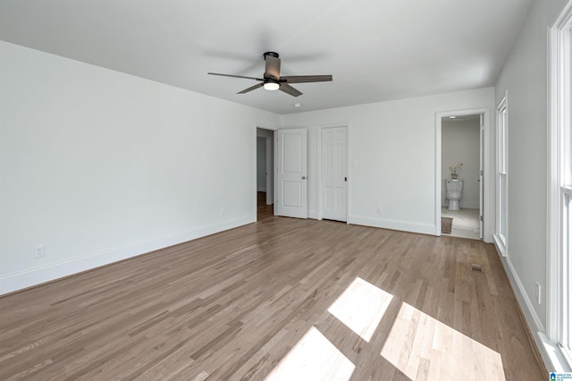 unfurnished bedroom featuring ceiling fan, light wood-style floors, ensuite bathroom, and baseboards
