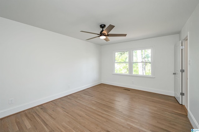 unfurnished room with light wood-style floors, baseboards, visible vents, and ceiling fan