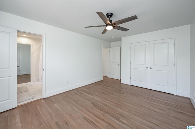 unfurnished bedroom featuring a closet, baseboards, light wood-type flooring, and ceiling fan