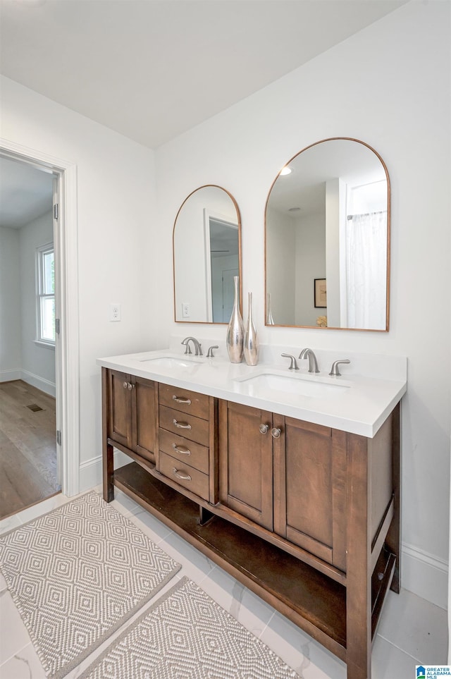 bathroom featuring tile patterned floors, double vanity, baseboards, and a sink