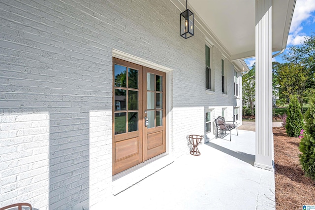 doorway to property featuring brick siding, french doors, and a patio