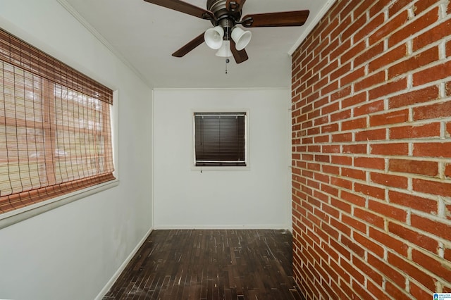 interior space featuring baseboards, brick wall, ornamental molding, a ceiling fan, and dark wood-type flooring