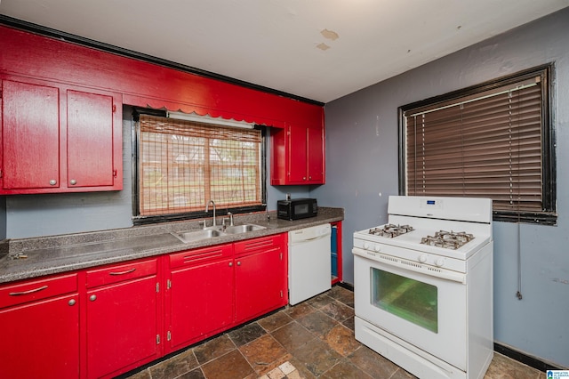 kitchen featuring stone finish flooring, white appliances, a sink, and red cabinetry