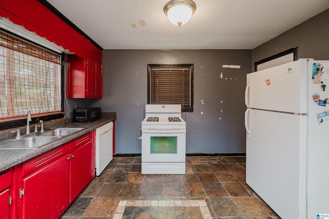 kitchen featuring red cabinetry, a sink, white appliances, and stone finish flooring