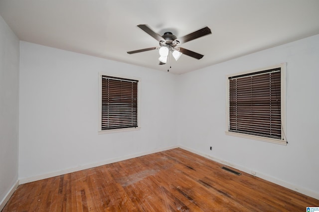 unfurnished room featuring wood-type flooring, visible vents, baseboards, and a ceiling fan