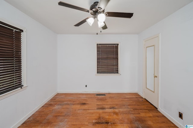 empty room with visible vents, ceiling fan, wood finished floors, and baseboards
