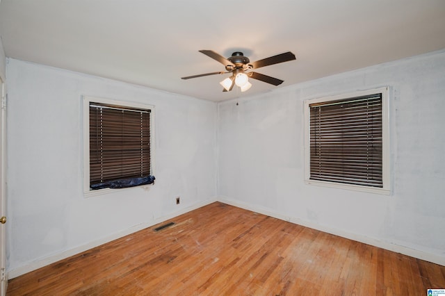 empty room featuring light wood-style floors, baseboards, a ceiling fan, and visible vents