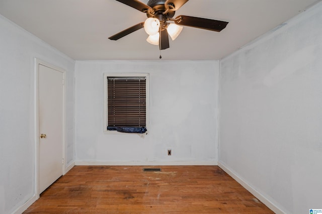 spare room with wood finished floors, ceiling fan, baseboards, and visible vents