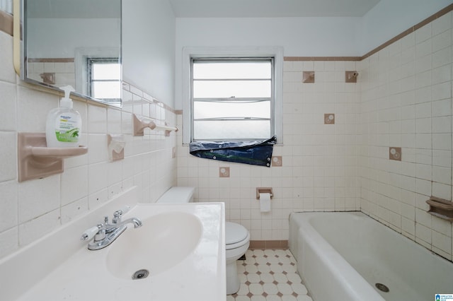 bathroom with a bathtub, tile walls, a sink, and toilet