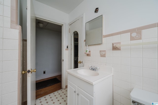 bathroom with toilet, tile patterned floors, tile walls, and vanity