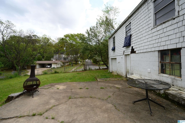 view of patio with an attached garage, fence, and a fire pit