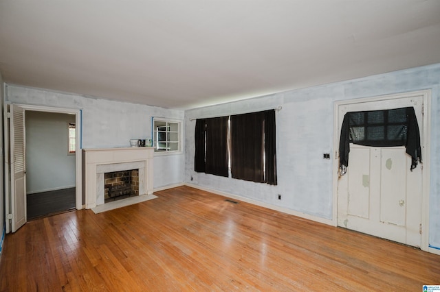unfurnished living room featuring hardwood / wood-style flooring and a fireplace with flush hearth