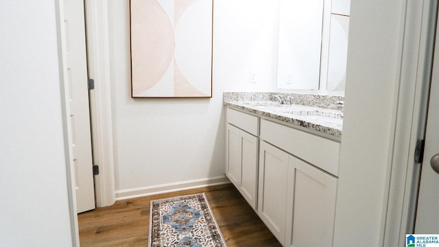 bathroom featuring double vanity, a sink, and wood finished floors