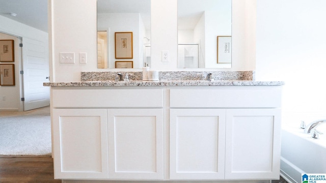 bathroom with a bathing tub, double vanity, and a sink