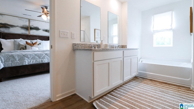 ensuite bathroom featuring ensuite bathroom, ceiling fan, a bath, vanity, and wood finished floors