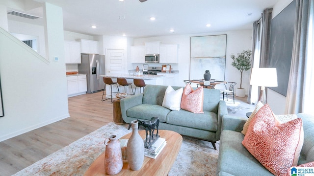 living area featuring visible vents, baseboards, ceiling fan, light wood-style floors, and recessed lighting