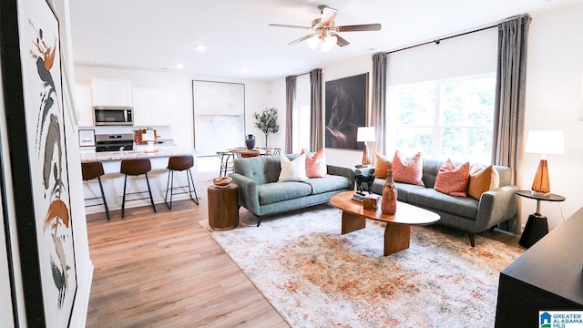 living room featuring ceiling fan, light wood finished floors, and recessed lighting