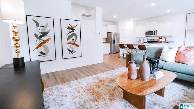 living area with recessed lighting, visible vents, and light wood-type flooring