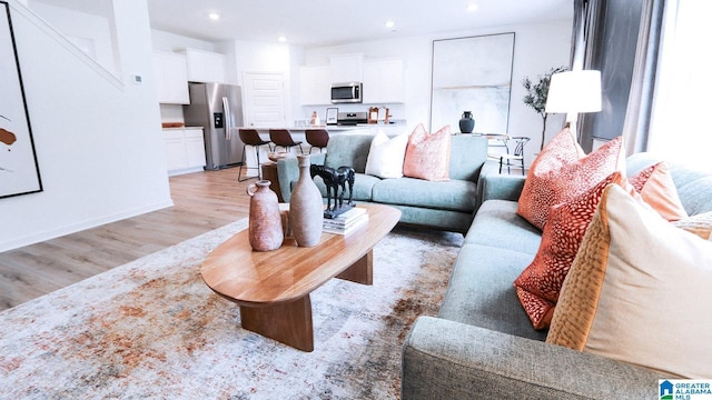 living area featuring baseboards, light wood finished floors, and recessed lighting