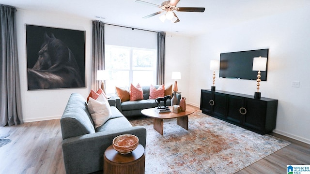 living room with ceiling fan, baseboards, visible vents, and wood finished floors