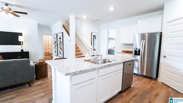 kitchen with light wood-style floors, ceiling fan, appliances with stainless steel finishes, a sink, and open floor plan
