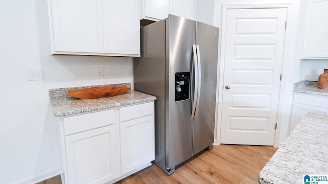 kitchen with light wood-style flooring, white cabinetry, light countertops, and stainless steel fridge