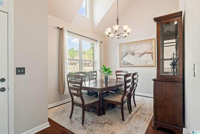 dining space with dark wood-type flooring, a notable chandelier, baseboards, and vaulted ceiling