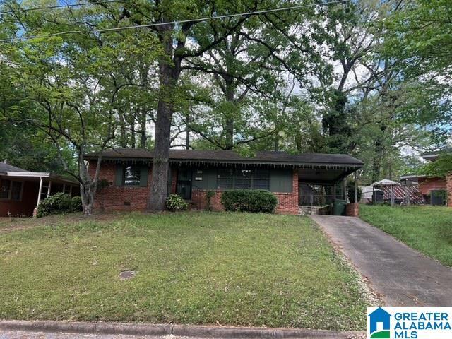 ranch-style house with brick siding, a front lawn, aphalt driveway, and an attached carport
