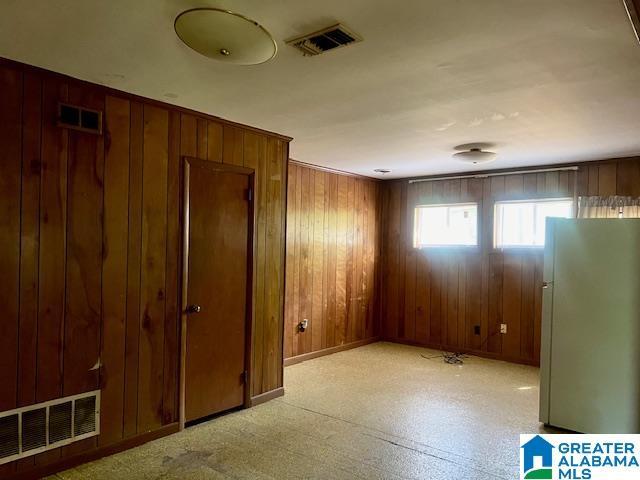 unfurnished room with visible vents, baseboards, and wooden walls