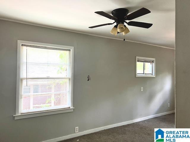 carpeted empty room featuring crown molding, baseboards, and ceiling fan