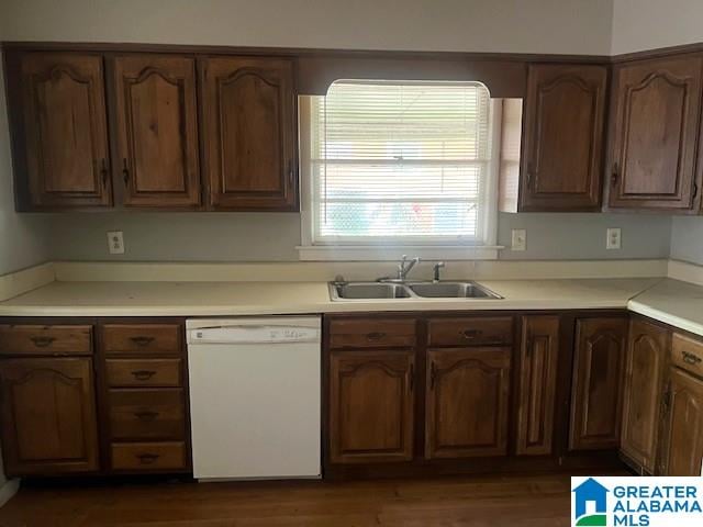 kitchen featuring white dishwasher, light countertops, dark wood finished floors, and a sink